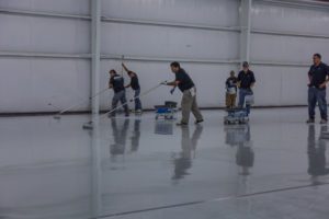 AIF field team laying a sleek, white glossy epoxy floor throughout a warehouse facility