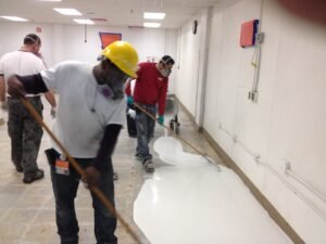 AIF laborers applying white epoxy floors to freshly prepared industrial facility