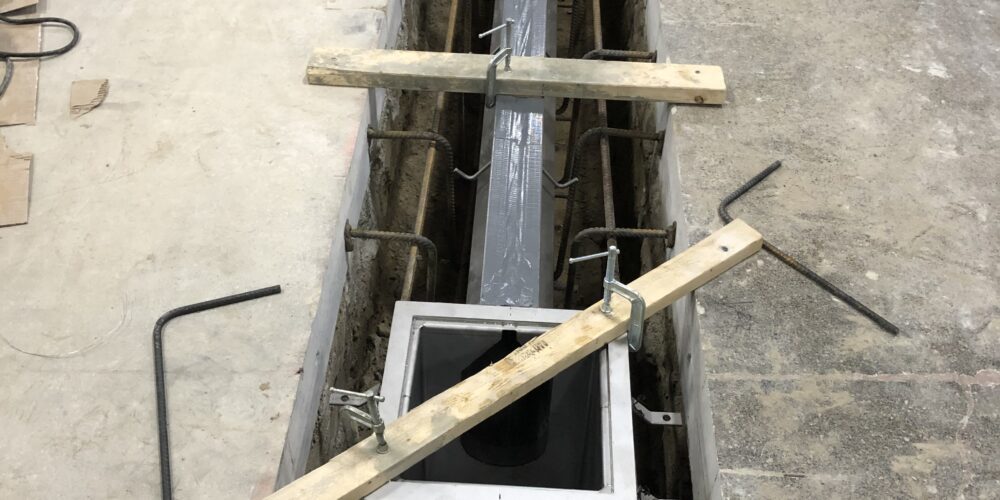 installation à mi-parcours de drains à fente en acier inoxydable dans un sol époxy antidérapant à trois couches dans un entrepôt de bouteilles de coca colas à Brampton, Ontario.